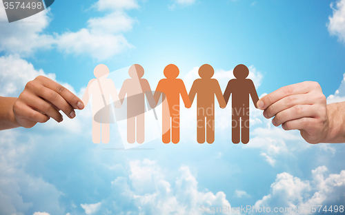 Image of hands holding chain of people pictogram over sky