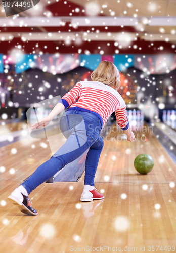 Image of happy young woman throwing ball in bowling club