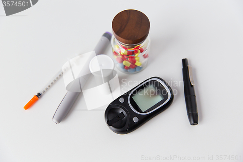 Image of close up of glucometer, insulin pen and drug pills