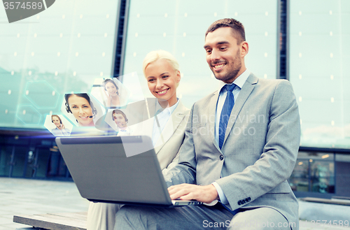 Image of smiling businesspeople with laptop outdoors