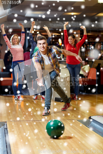 Image of happy young man throwing ball in bowling club