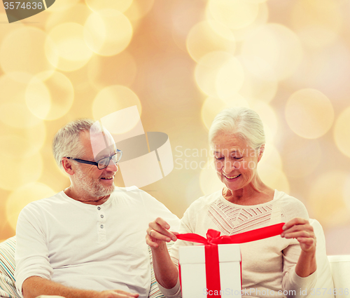 Image of happy senior couple with gift box at home