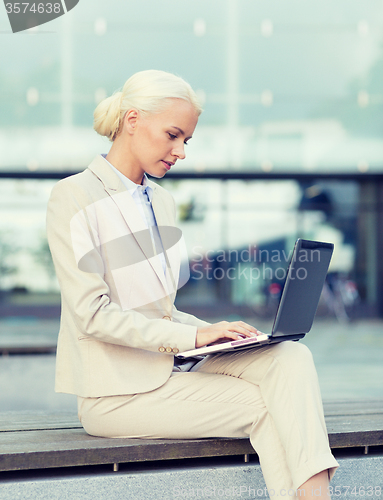 Image of businesswoman working with laptop outdoors