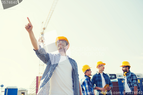 Image of group of smiling builders in hardhats outdoors