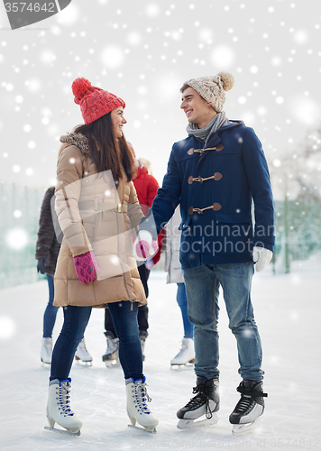 Image of happy friends ice skating on rink outdoors