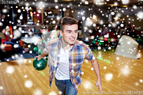 Image of happy young man throwing ball in bowling club