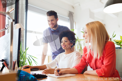 Image of happy creative team with computer in office