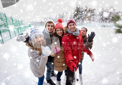 Image of happy friends with smartphone on ice skating rink