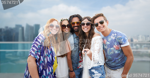 Image of happy hippie friends with selfie stick over city