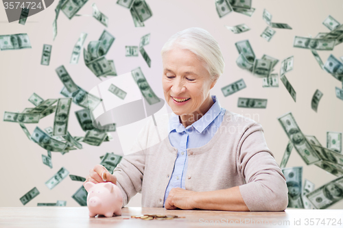 Image of senior woman putting money to piggy bank at home