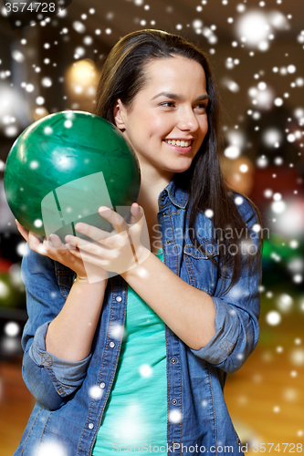 Image of happy young woman holding ball in bowling club