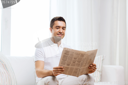 Image of happy man reading newspaper at home