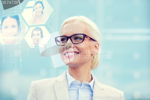 Image of young smiling businesswoman in eyeglasses outdoors