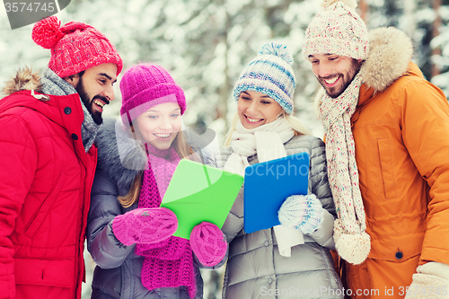 Image of smiling friends with tablet pc in winter forest