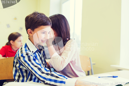 Image of smiling schoolgirl whispering to classmate ear