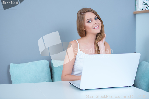 Image of Young Woman Sitting at Table with Laptop Computer