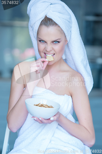 Image of Woman in Bath Towel Eating Snacks from Bowl