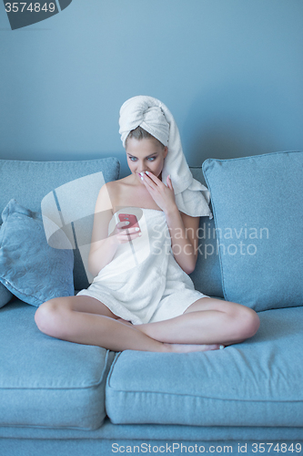 Image of Woman in Bath Towel with Cell Phone on Sofa