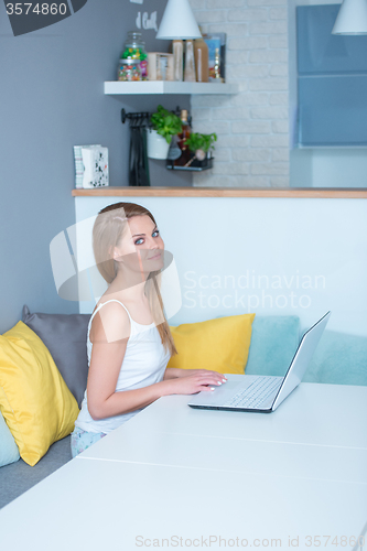 Image of Young Woman Sitting at Table with Laptop Computer