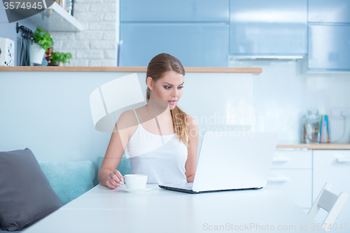 Image of Woman Sitting at Table with Laptop and Mug