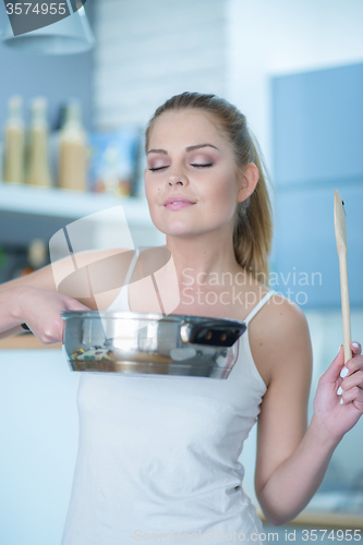 Image of Young woman savoring the smell of her cooking