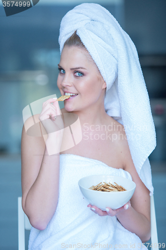 Image of Woman in Bath Towel Eating Snacks from Bowl