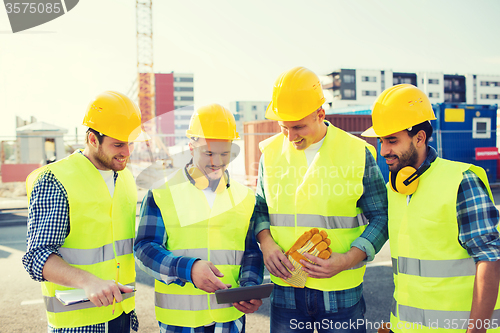Image of group of smiling builders with tablet pc outdoors