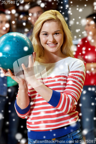 Image of happy young woman holding ball in bowling club