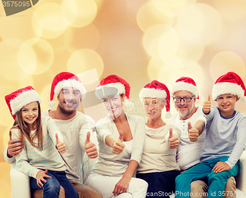 Image of happy family in santa hats showing thumbs up