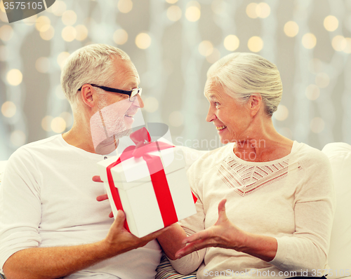 Image of happy senior couple with gift box at home