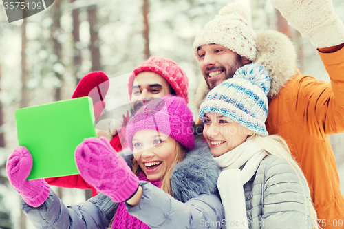 Image of smiling friends with tablet pc in winter forest