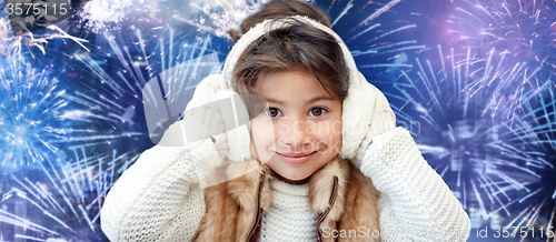 Image of happy little girl wearing earmuffs over firework