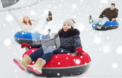 Image of group of happy friends sliding down on snow tubes