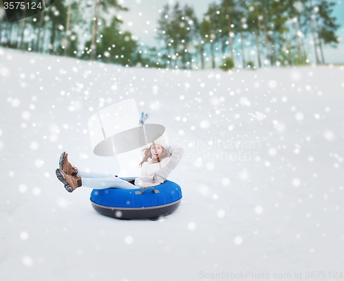 Image of happy teenage girl sliding down on snow tube