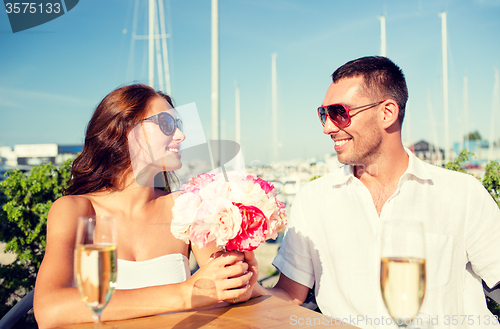 Image of smiling couple with bunch and champagne at cafe