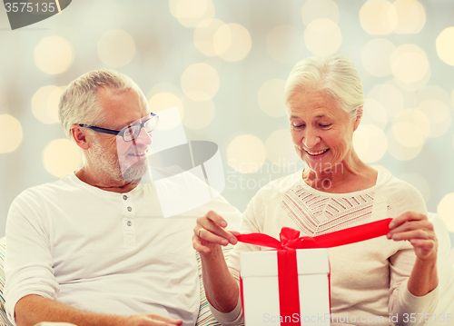 Image of happy senior couple with gift box at home