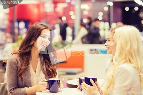 Image of smiling young women drinking coffee in mall 