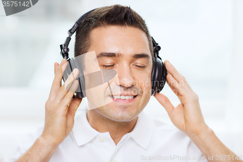 Image of happy man in headphones listening to music at home