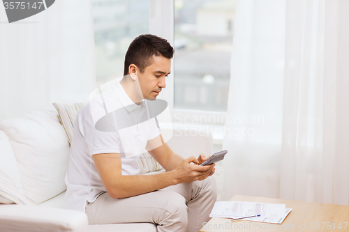 Image of man with papers and calculator at home