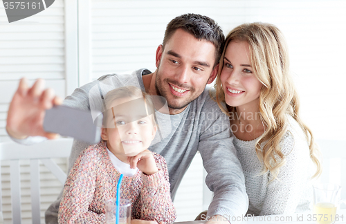 Image of happy family taking selfie at restaurant