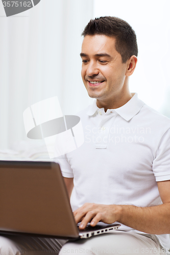 Image of happy man working with laptop computer at home