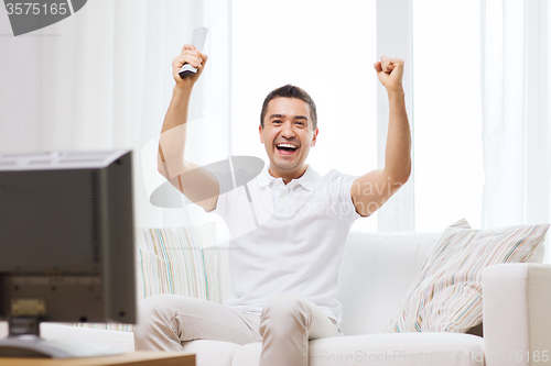 Image of smiling man watching sports at home