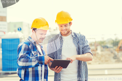 Image of smiling builders in hardhats with tablet pc