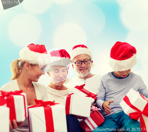 Image of happy family in santa helper hats with gift boxes