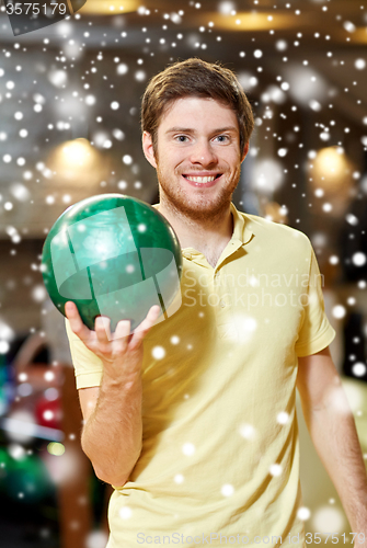 Image of happy young man holding ball in bowling club