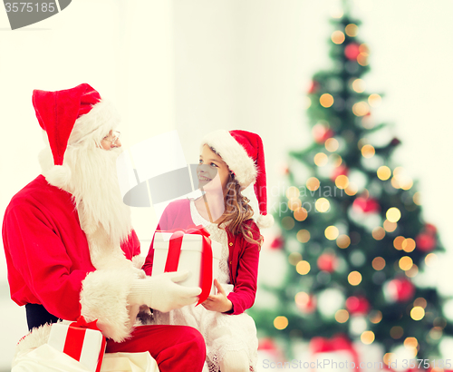 Image of smiling little girl with santa claus and gifts