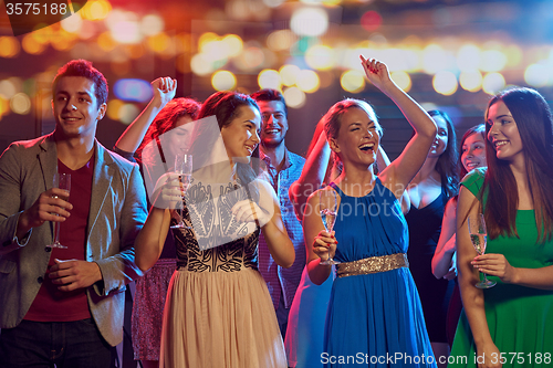 Image of happy friends with champagne dancing at nightclub