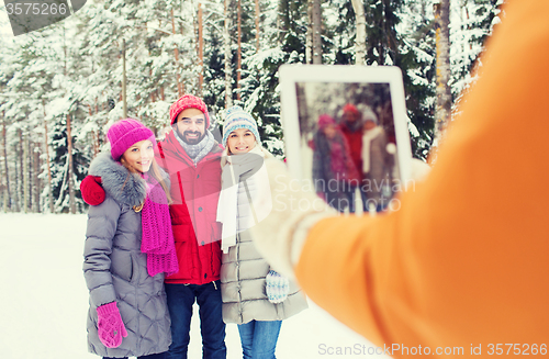 Image of smiling friends with tablet pc in winter forest