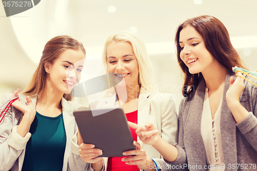 Image of happy young women with tablet pc and shopping bags