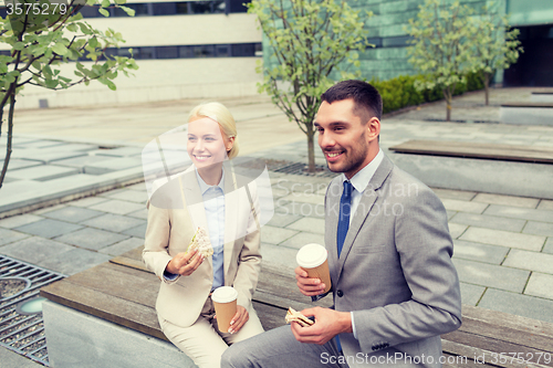 Image of smiling businessmen with paper cups outdoors